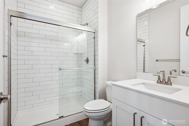 full bath with toilet, a shower stall, wood finished floors, and vanity
