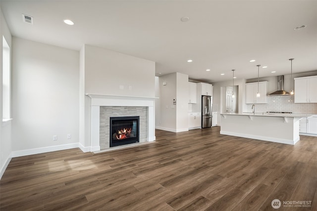 unfurnished living room featuring recessed lighting, visible vents, a sink, and dark wood-type flooring