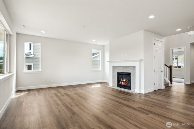 unfurnished living room featuring baseboards, a fireplace, wood finished floors, and stairway