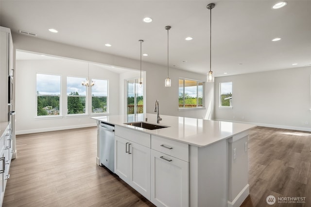 kitchen featuring a sink, light countertops, wood finished floors, stainless steel dishwasher, and visible vents