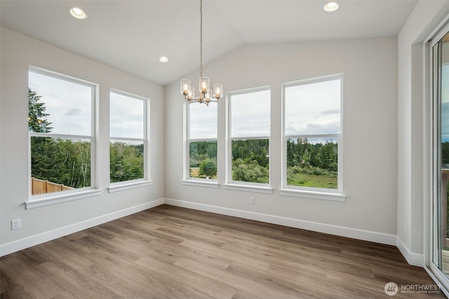 unfurnished dining area featuring vaulted ceiling, wood finished floors, baseboards, a notable chandelier, and recessed lighting