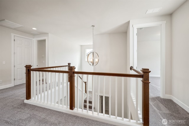 hallway featuring an inviting chandelier, carpet floors, baseboards, an upstairs landing, and visible vents