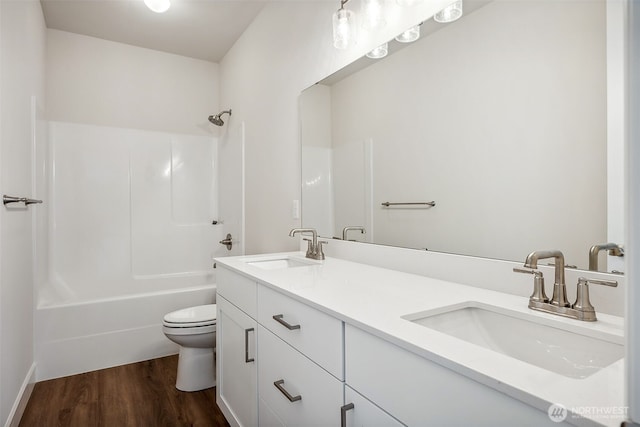 bathroom featuring double vanity, a sink, wood finished floors, and toilet