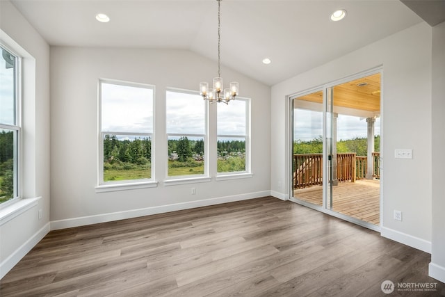 unfurnished dining area featuring wood finished floors, lofted ceiling, baseboards, recessed lighting, and a notable chandelier