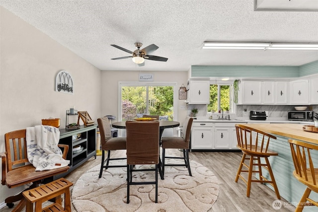 16 Harrison St, South Bend, WA 98586 - dining room featuring light wood-style floors, a textured ceiling, and ceiling fan