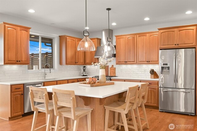 3679 Silver Oak Ct, Bellingham, WA 98226 - kitchen with decorative backsplash, a kitchen island, appliances with stainless steel finishes, a sink, and wall chimney exhaust hood
