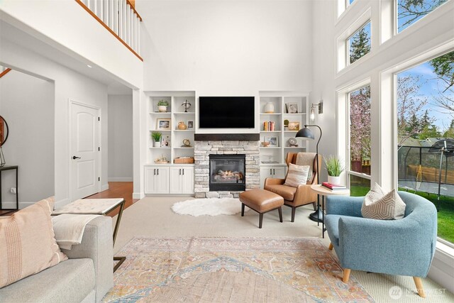 3679 Silver Oak Ct, Bellingham, WA 98226 - living room featuring built in features, a high ceiling, a stone fireplace, and baseboards