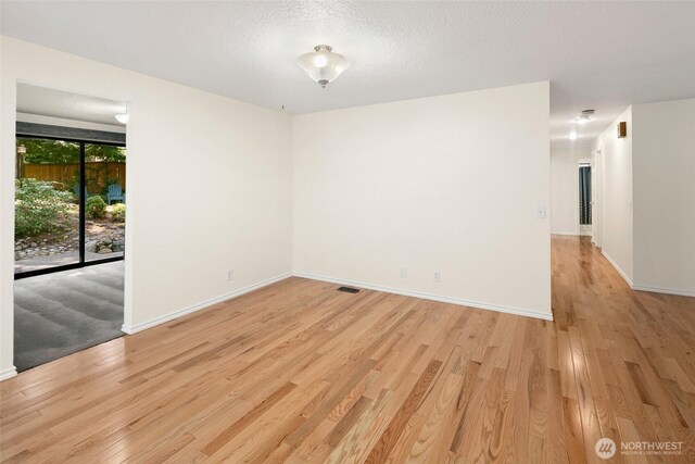 empty room featuring baseboards, light wood-style flooring, and visible vents