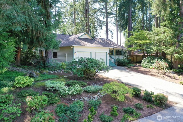 view of home's exterior with fence, an attached garage, concrete driveway, and a shingled roof