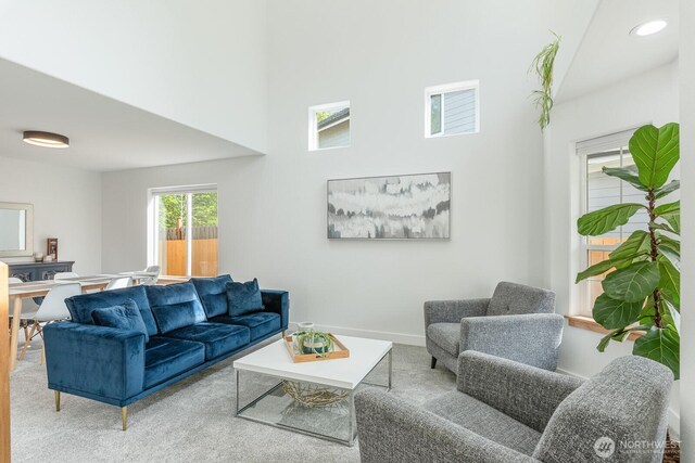living room with visible vents, baseboards, carpet, and a high ceiling