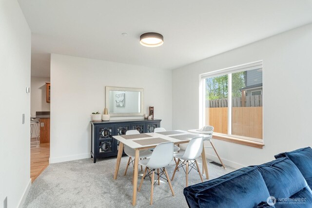 dining area featuring baseboards and light carpet