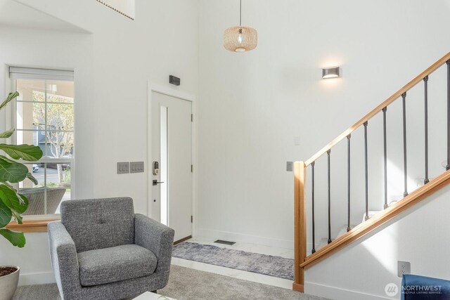 foyer entrance featuring stairs, baseboards, and a towering ceiling