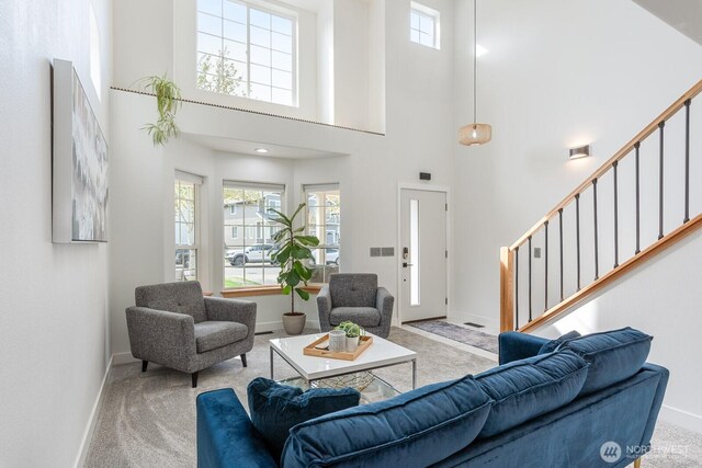 carpeted living room featuring baseboards, plenty of natural light, and a high ceiling
