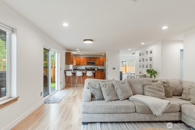 living room featuring recessed lighting, baseboards, and light wood-style floors