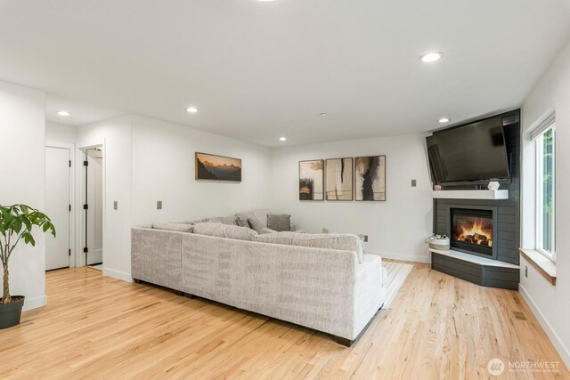 living room featuring recessed lighting, baseboards, a fireplace, and light wood-type flooring