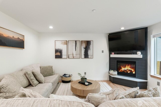 living room with recessed lighting, a large fireplace, baseboards, and light wood finished floors