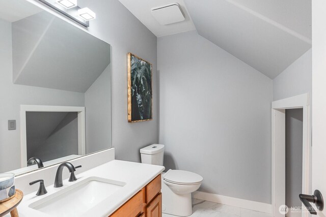 bathroom featuring vanity, vaulted ceiling, toilet, and marble finish floor