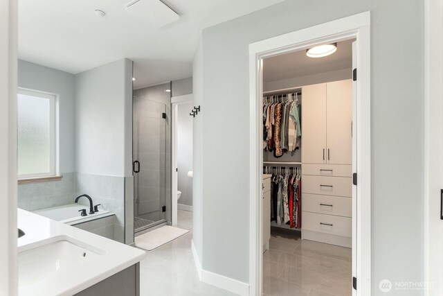 full bath featuring vanity, a walk in closet, baseboards, and a shower stall