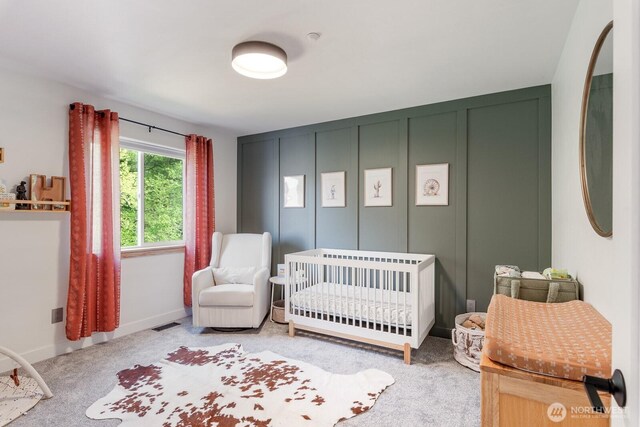 carpeted bedroom featuring a nursery area and visible vents