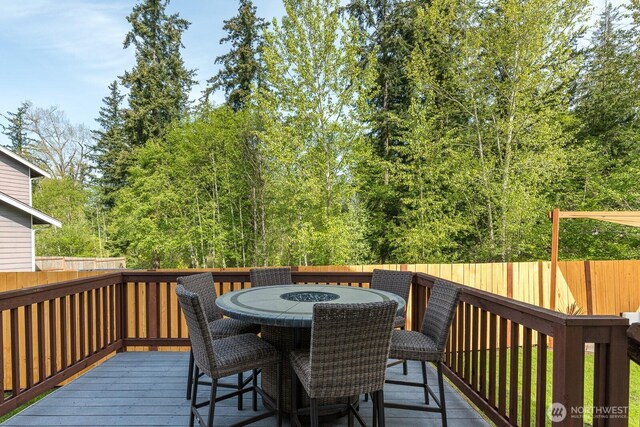wooden terrace featuring outdoor dining space and a fenced backyard