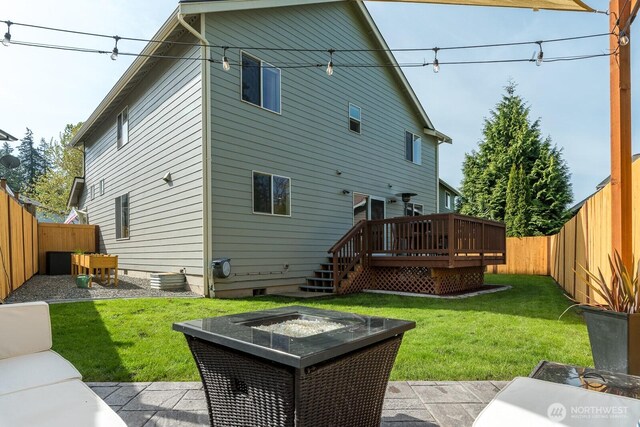 back of property with a deck, crawl space, a fire pit, and a fenced backyard