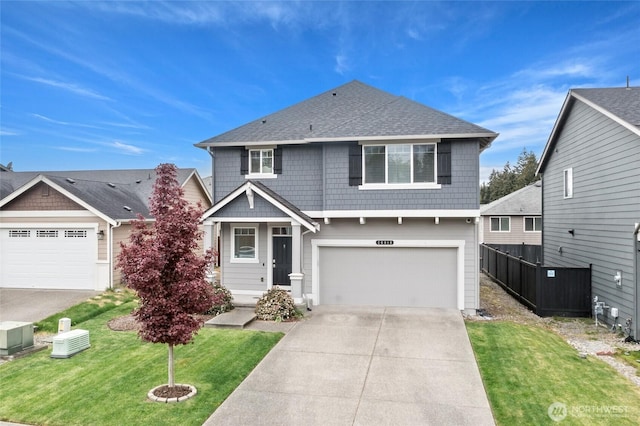traditional home featuring fence, a front yard, roof with shingles, an attached garage, and driveway