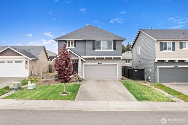 view of front facade featuring an attached garage, fence, driveway, and a front yard