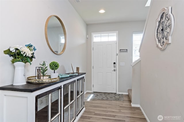 foyer entrance featuring light wood-type flooring, stairway, baseboards, beverage cooler, and recessed lighting