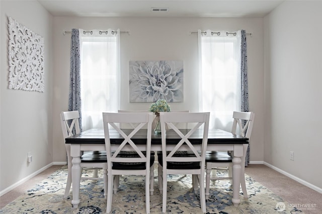 carpeted dining area featuring visible vents, baseboards, and a wealth of natural light
