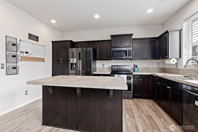 kitchen featuring a center island, a sink, light wood finished floors, and appliances with stainless steel finishes