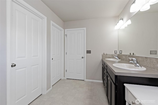 bathroom with double vanity, a sink, baseboards, and tile patterned floors