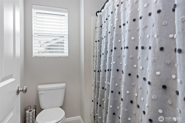 bathroom featuring baseboards, toilet, and a shower with curtain