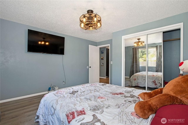 bedroom featuring a textured ceiling, a chandelier, baseboards, wood finished floors, and a closet