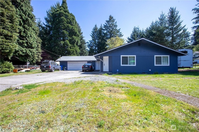 ranch-style house featuring a front yard and a detached garage