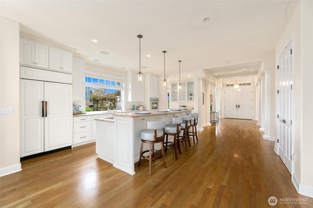 9676 Evergreen Dr, Bellevue, WA 98004 - kitchen with stainless steel oven, a kitchen island, paneled fridge, wood finished floors, and white cabinetry