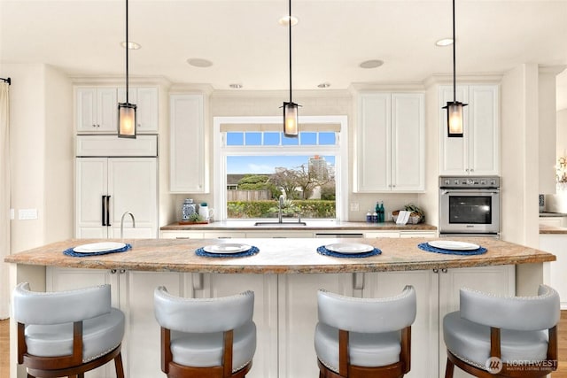 9676 Evergreen Dr, Bellevue, WA 98004 - kitchen with stainless steel oven, a sink, paneled built in refrigerator, a center island, and a breakfast bar area