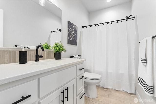 bathroom with vanity, toilet, wood finished floors, and shower / tub combo with curtain