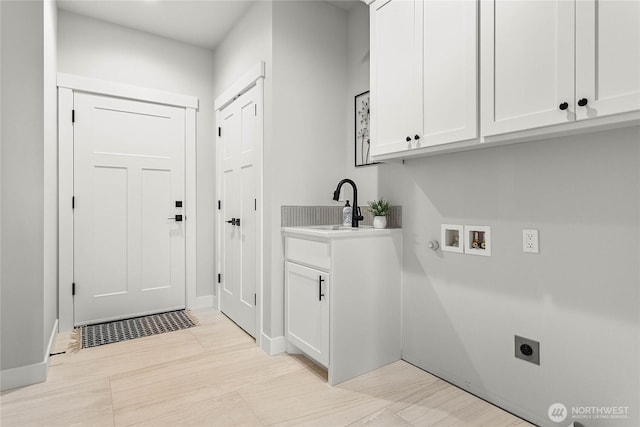 laundry room featuring hookup for an electric dryer, cabinet space, a sink, baseboards, and hookup for a washing machine