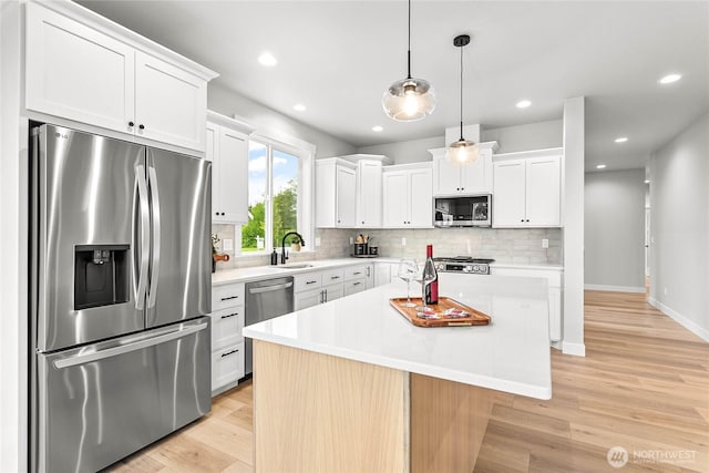 kitchen with light countertops, light wood finished floors, appliances with stainless steel finishes, and backsplash