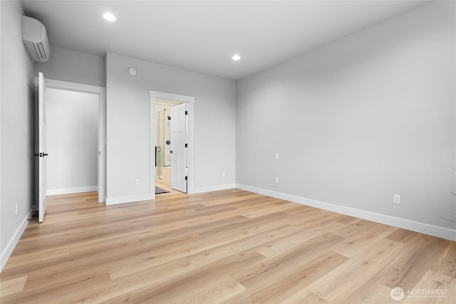 unfurnished bedroom featuring baseboards, light wood-style floors, and a wall unit AC