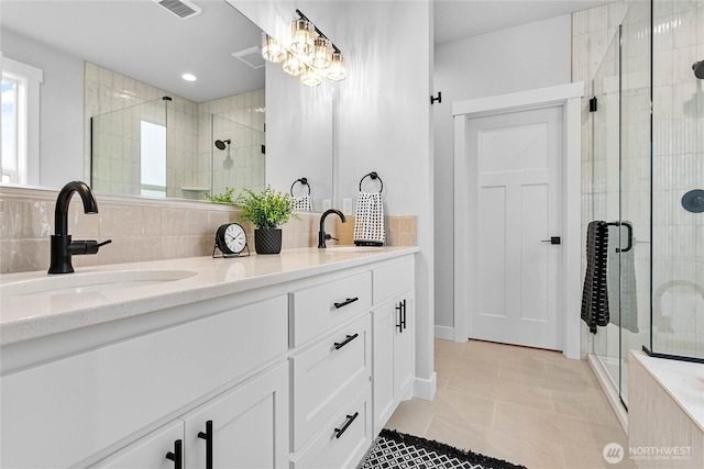 full bath featuring a sink, tile patterned floors, a shower stall, and double vanity