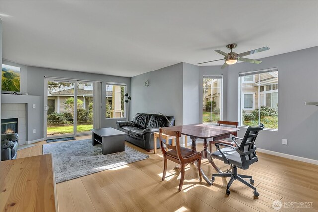 dining area featuring a healthy amount of sunlight, baseboards, a fireplace, and light wood-type flooring