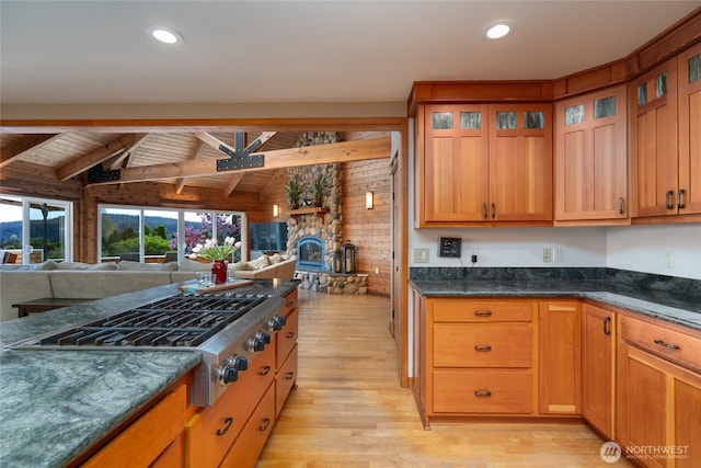 15089 Old Deception Mill Ln, Anacortes, WA 98221 - kitchen with glass insert cabinets, open floor plan, wooden walls, light wood-style flooring, and stainless steel gas stovetop