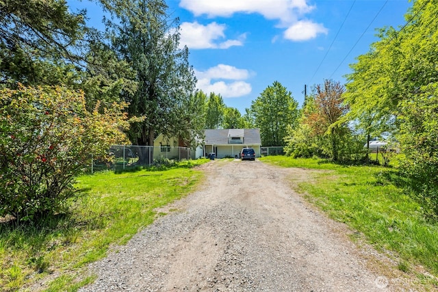 obstructed view of property with dirt driveway and fence