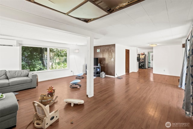 living room with a wall mounted air conditioner, wood finished floors, and baseboards
