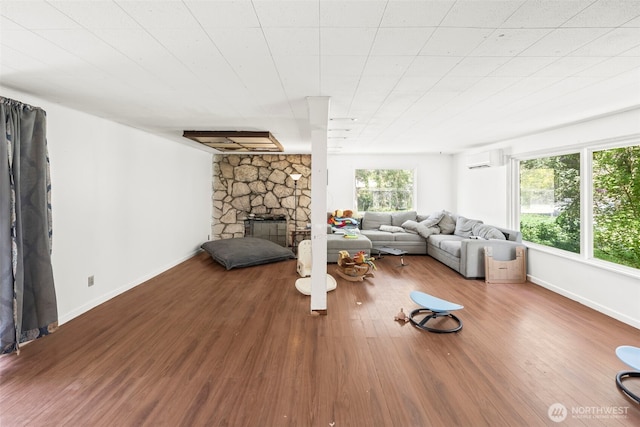 living area featuring an AC wall unit, wood finished floors, and baseboards