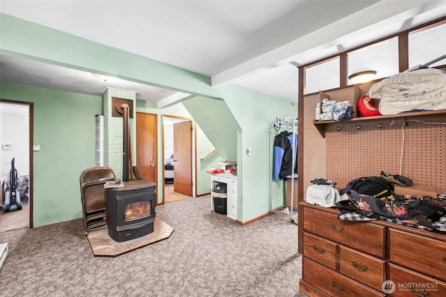 bedroom featuring a wood stove, carpet, and beamed ceiling