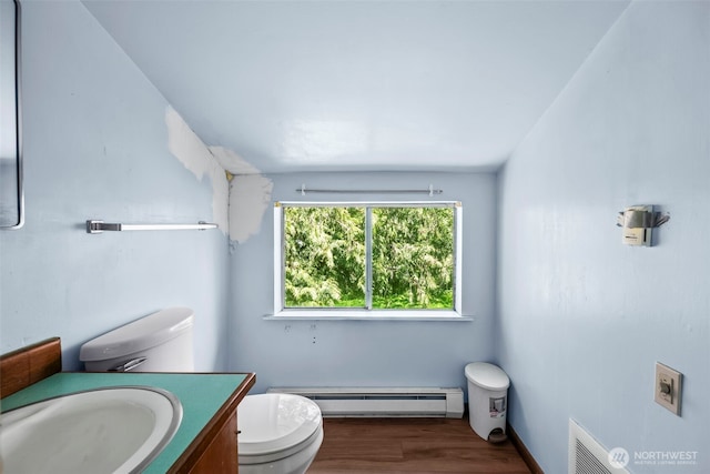 half bathroom with a baseboard radiator, toilet, wood finished floors, and vanity