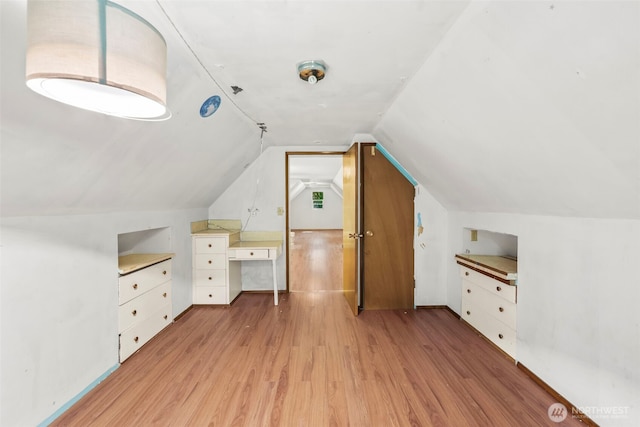 additional living space featuring light wood-style floors and vaulted ceiling
