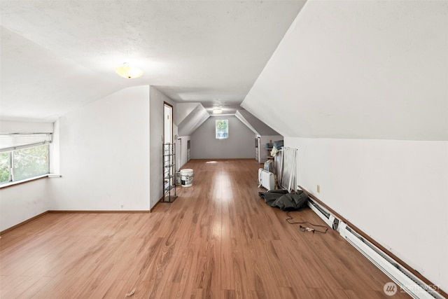 bonus room with lofted ceiling, light wood-style floors, and baseboards
